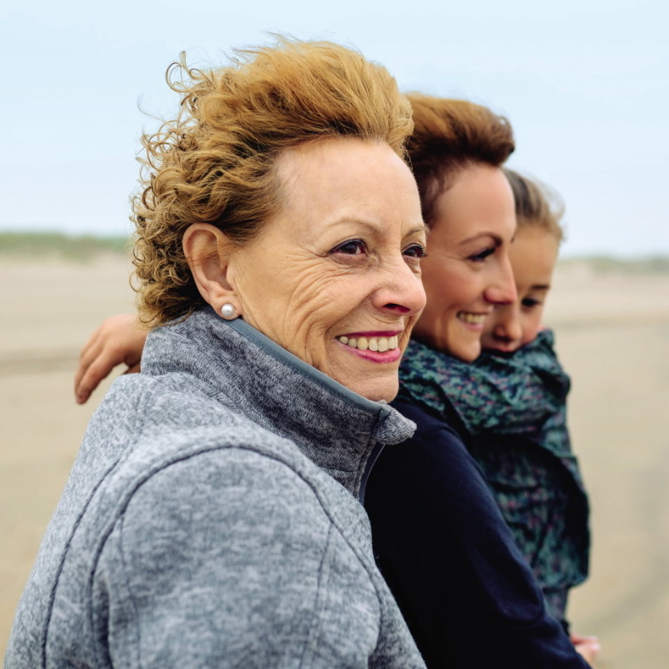 Older woman, young woman and a girl standing outside and smiling