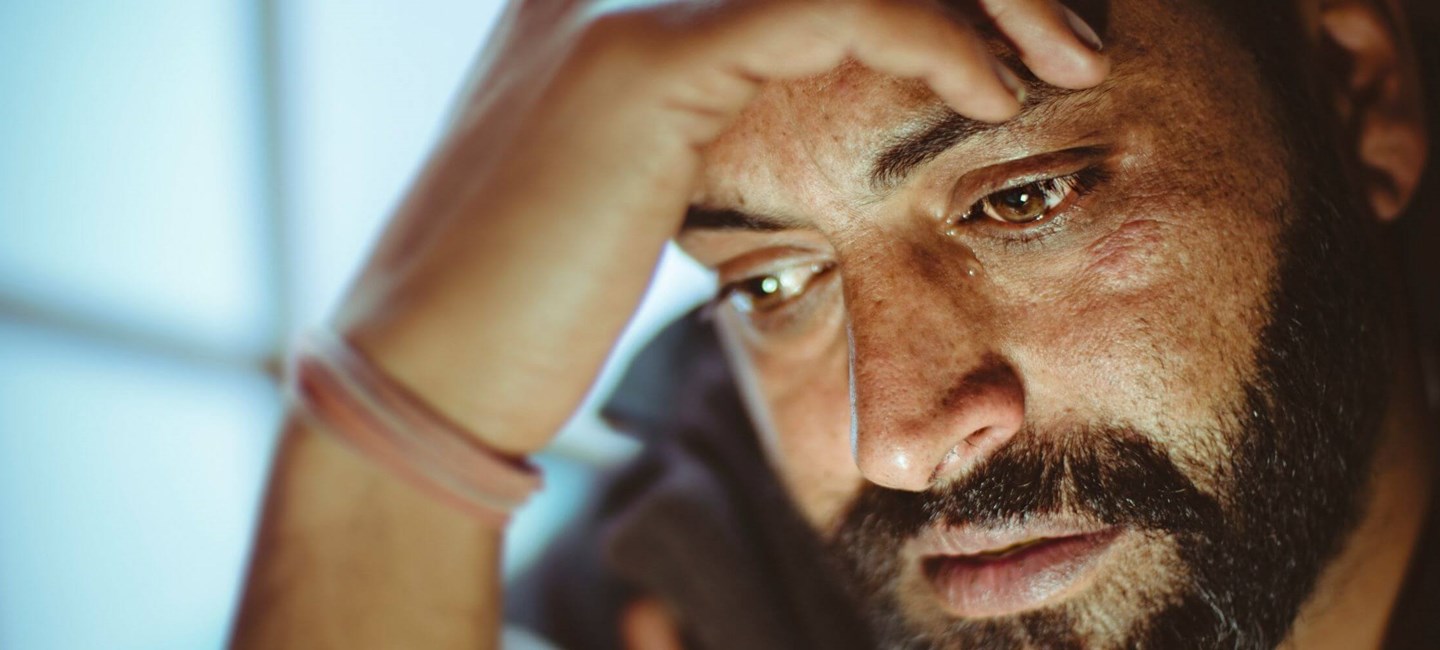 Depressed man holding hand on his forehead