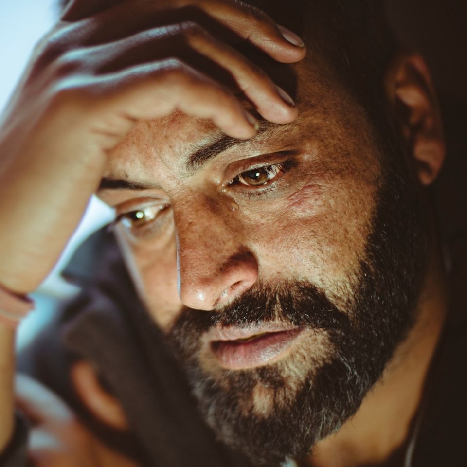 Depressed man holding hand on his forehead
